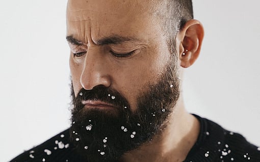 Man looking at crumbles of polystyrene on his shirt and beard.