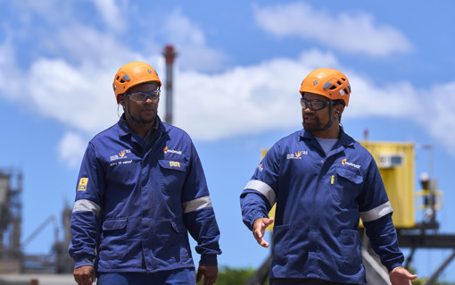 Two Mondi colleagues in hard hats walk outside of a manufacturing plant.