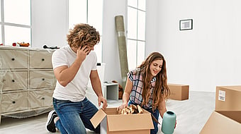 A man and a woman unpacking items from a corrugated box