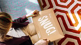 A woman holding a Mondi EnvelopeMailer in her hands with the word "Snug" printed on it.