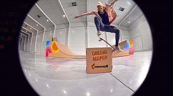 Olympic skateboarder Julia Bruckler performing an ollie over a carboard box with "challenge accepted" written on it and designed by Mondi.