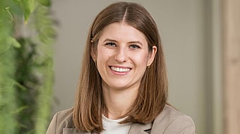 Profile picture of Vera, a young woman with light brown long hair and blue eyes, smiling friendly into the camera