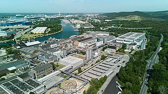 Aerial view of Mondi's Duino mill, located beside a canal and surrounded by green landscape.