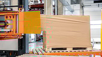 Automated stretch wrapping machine applying film around a palletized load in a warehouse.