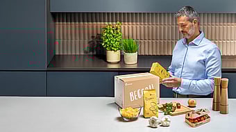 man standing at kitchen counter examining text on food packaging