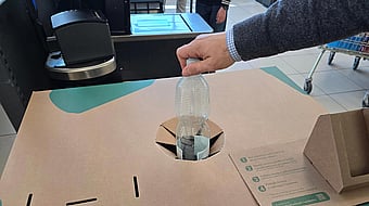 hand placing a plastic bottle into a recycling box