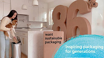 Person placing packaging into a kitchen recycling bin beside a large cardboard display featuring the text “86% want sustainable packaging” and “Inspiring packaging for generations.” The scene highlights sustainable packaging and recycling in a home environment.