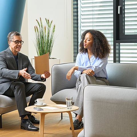 Two colleagues seated in a modern office, discussing a document.