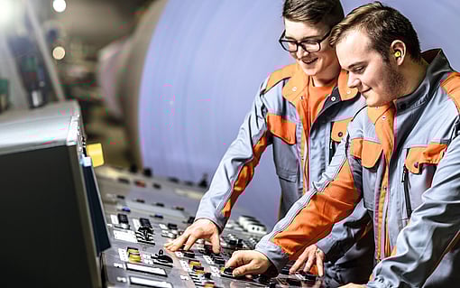 Two young male employees working in the control room of a production