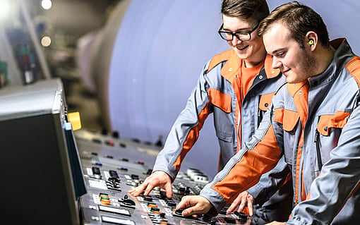 Two young male employees working in the control room of a production