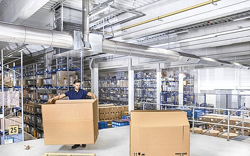 A person assembling a corrugated box for heavy goods.