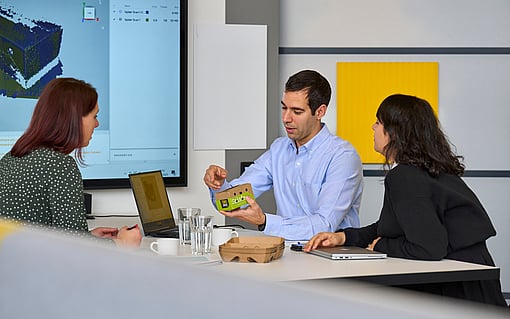 Mitarbeiter:innen besprechen eine Verpackung