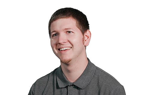 Shoulders up shot of man in a grey polo shirt with short brown hair