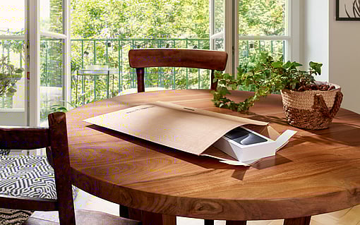 An opened ProtectiveMailer with a smartphone inside, lying on a table.