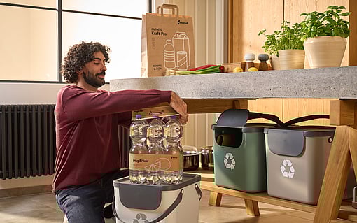 A man opening a PET six-pack of water bottles packaged with the Mondi Hug & Hold solution.