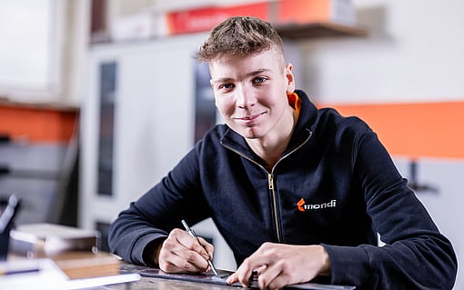 young boy in black zip up jacket holding a pen and smiling