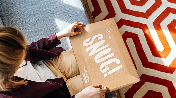 A woman holding a Mondi EnvelopeMailer in her hands with the word "Snug" printed on it.