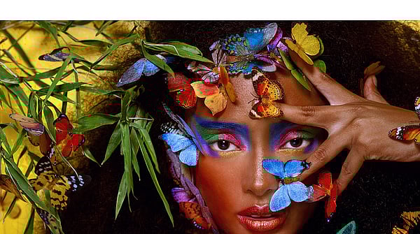 A woman surrounded by colourful butterflies and plants.