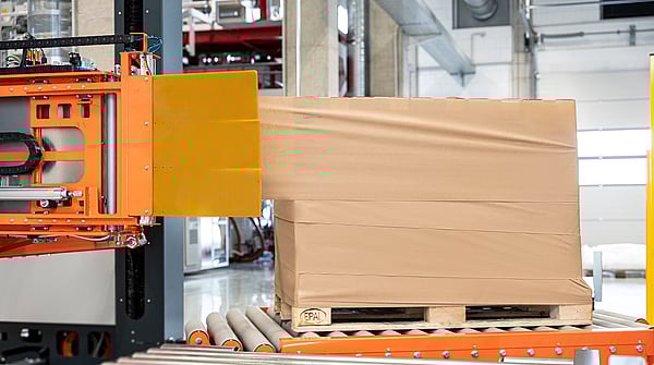 Automated stretch wrapping machine applying film around a palletized load in a warehouse.