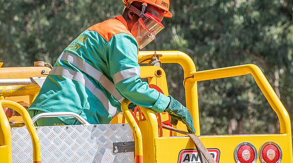 Worker with blue safety equipment and safety glasses is working on top of a yellow car.