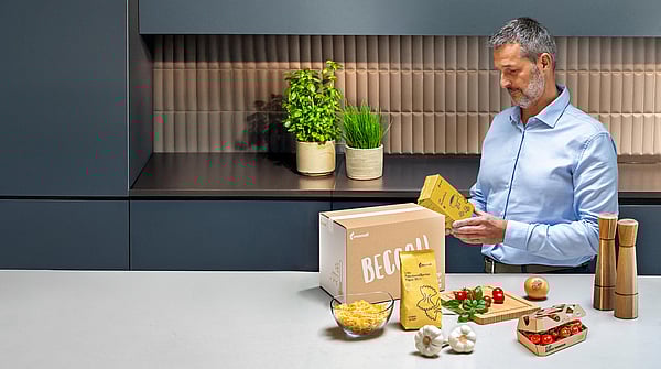 man standing at kitchen counter examining text on food packaging