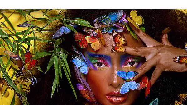 A woman surrounded by colourful butterflies and plants.