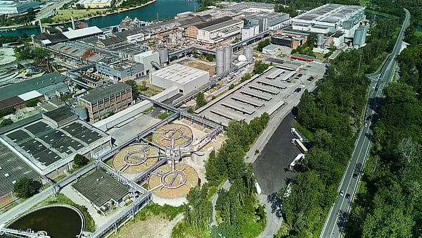 Aerial view of Mondi's Duino mill, located beside a canal and surrounded by green landscape.