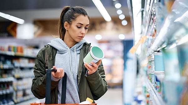 A young woman is reading a nutrition label while shopping.
