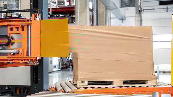 Automated stretch wrapping machine applying film around a palletized load in a warehouse.