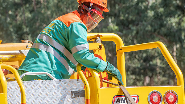 Worker with blue safety equipment and safety glasses is working on top of a yellow car.