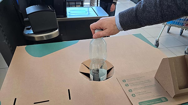 hand placing a plastic bottle into a recycling box