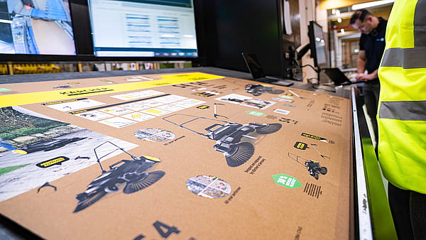 man in hi-vis jacket overlooking a machine printing imagery and text onto a cardboard box