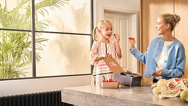a woman and a girl in a kitchen eating food