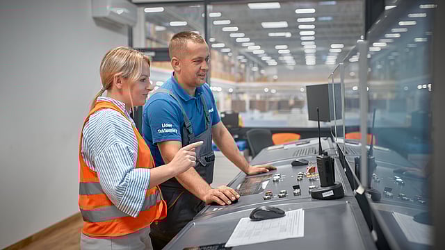 a man and a woman in safety gear operating machinery in a factory