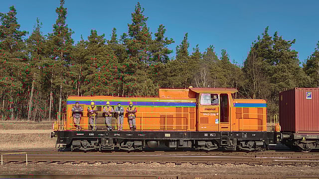 orange train with five men leaning against it