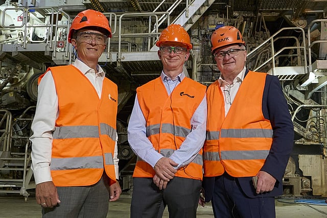 Mondi executives wearing protective gear, standing in front of a new Mill machine with pipes visible.