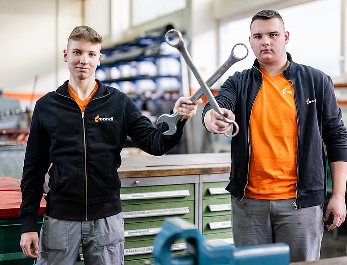 young boy in black zip up jacket holding a pen and smiling