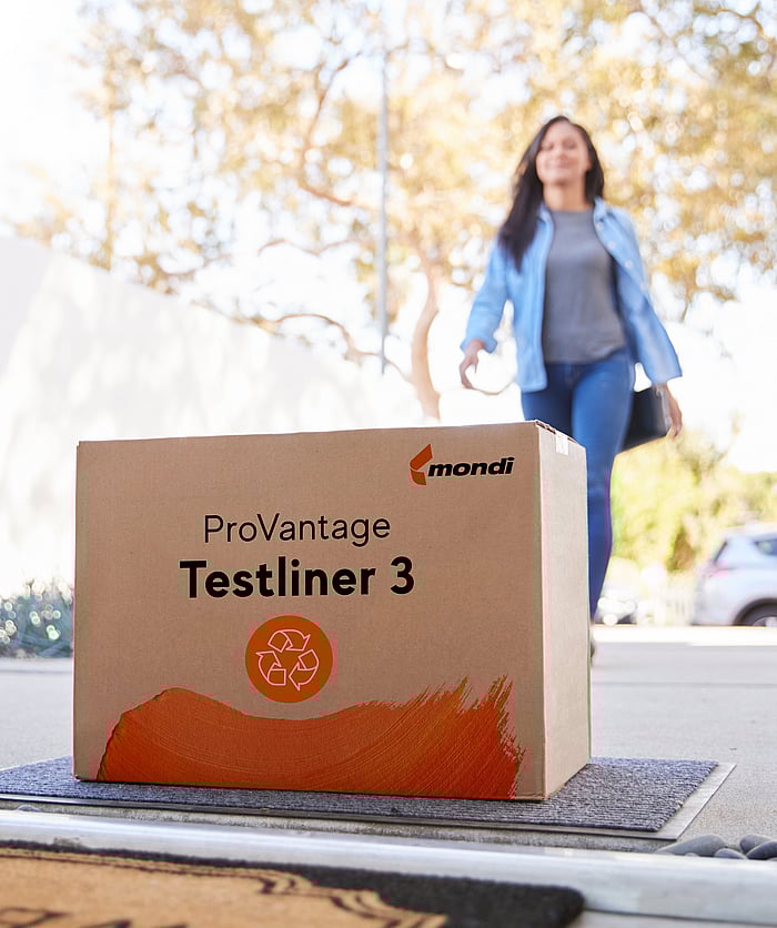 A woman walks into a house. At the doorstep lies a brown corrugated box with the writing ProVantage Testliner 3.