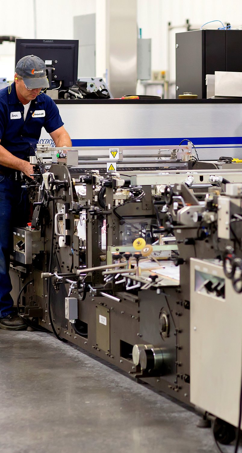 man in blue top and blue trousers working at a machine in a factory