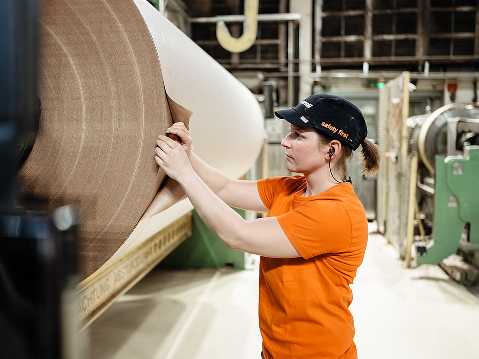 Woman in production next to paper reel
