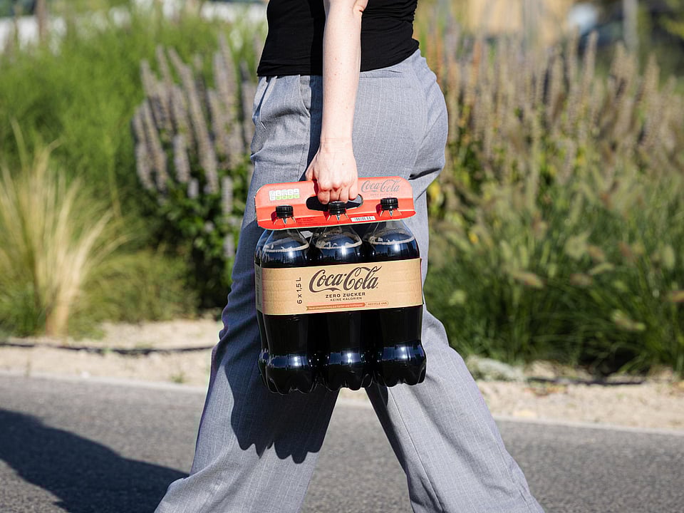 Person holding a multi pack of Coca cola bottles