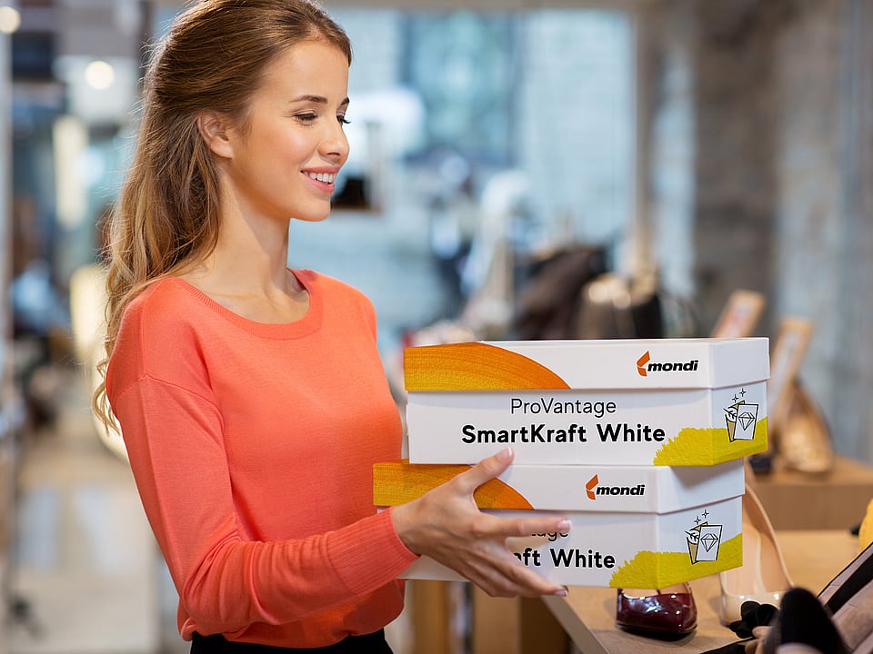 A woman holding a corrugated box with the words ProVantage SmartKraft White written on it.
