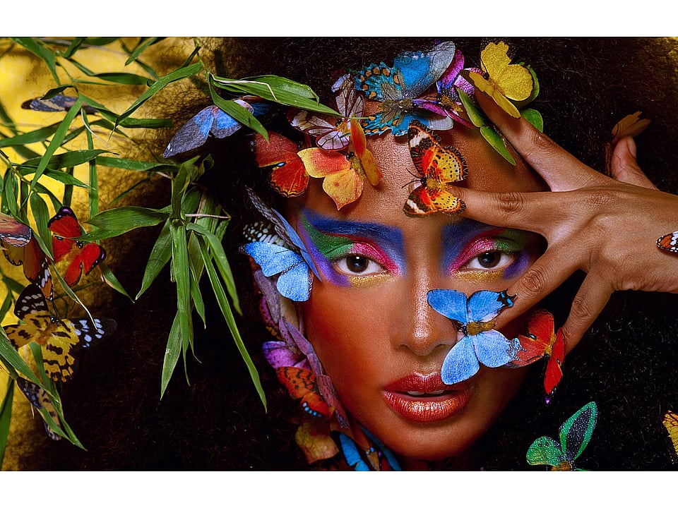 A woman surrounded by colourful butterflies and plants.