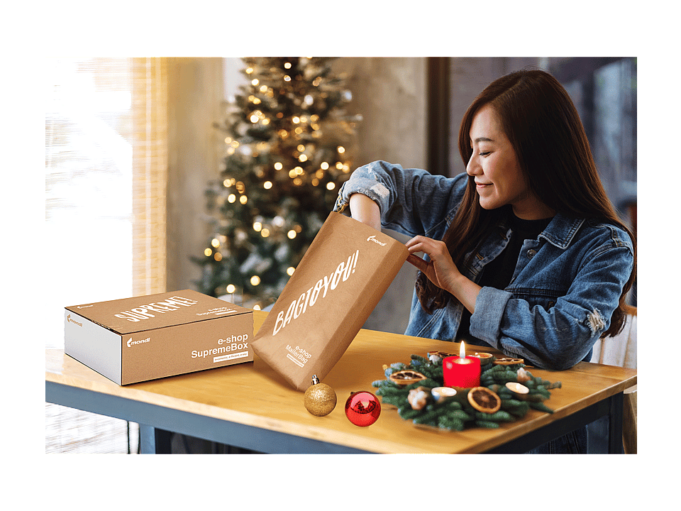 A woman in a room decorated for Christmas is unpacking items from a Mondi MailerBag und Mondi SupremeBox