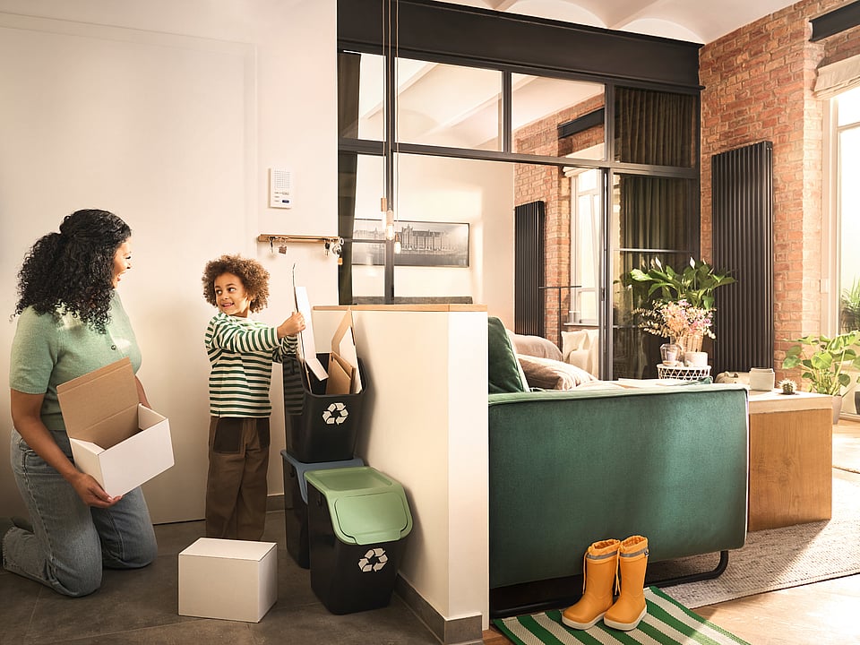 A woman and a boy in a kitchen area sorting corrugated boxes.