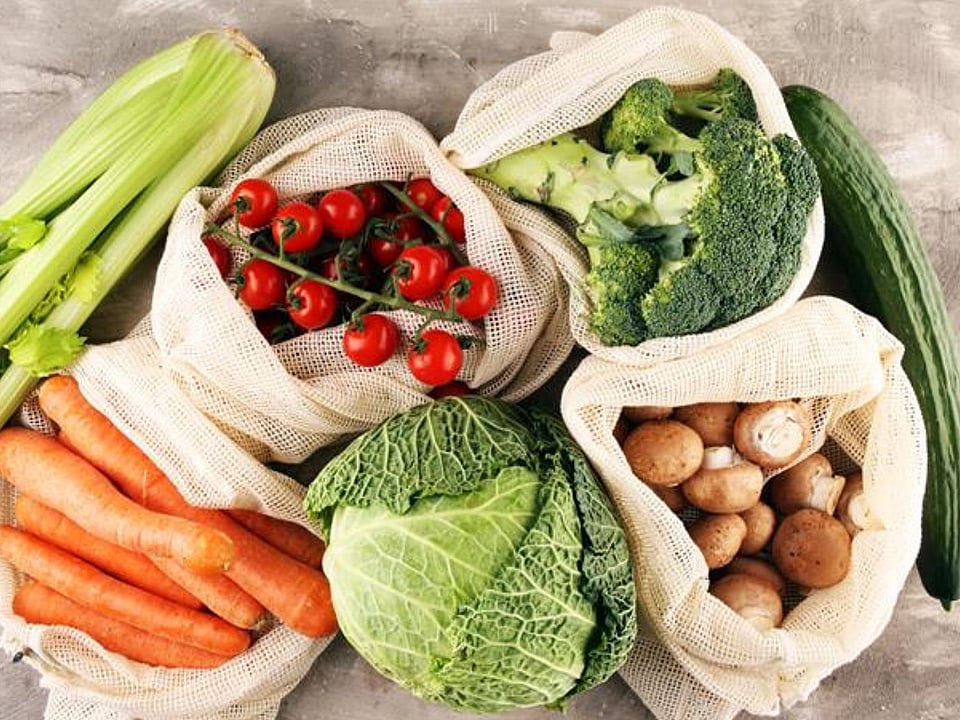 there are different types of vegetables on a grey background. There are tomatoes, cucumber, carrots, cabbage and broccoli.