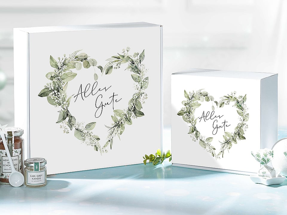 A white corrugated gift box featuring a floral heart-shaped design and the inscription in German, "Alles Gute."