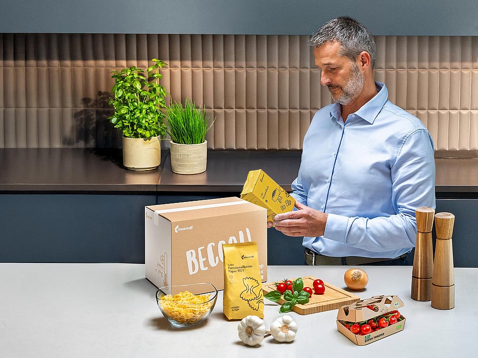 man standing at kitchen counter examining text on food packaging