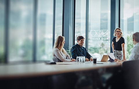 A group of people having a conversation around a table in a virtual ThinkBox space.
