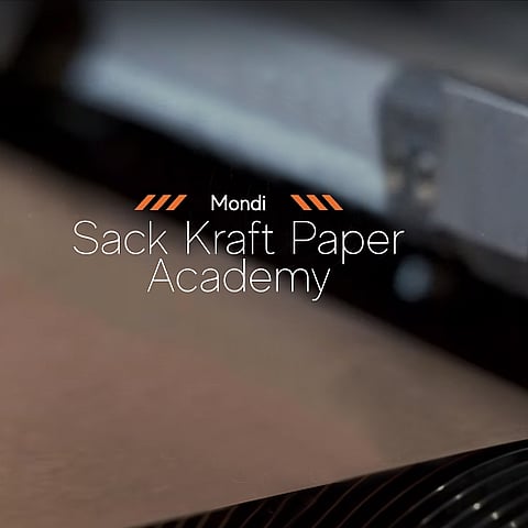 A promotional graphic for the Mondi Sack Kraft Paper Academy featuring the text “Sack Kraft Paper Academy” over a close-up background image of paper moving through industrial manufacturing equipment.